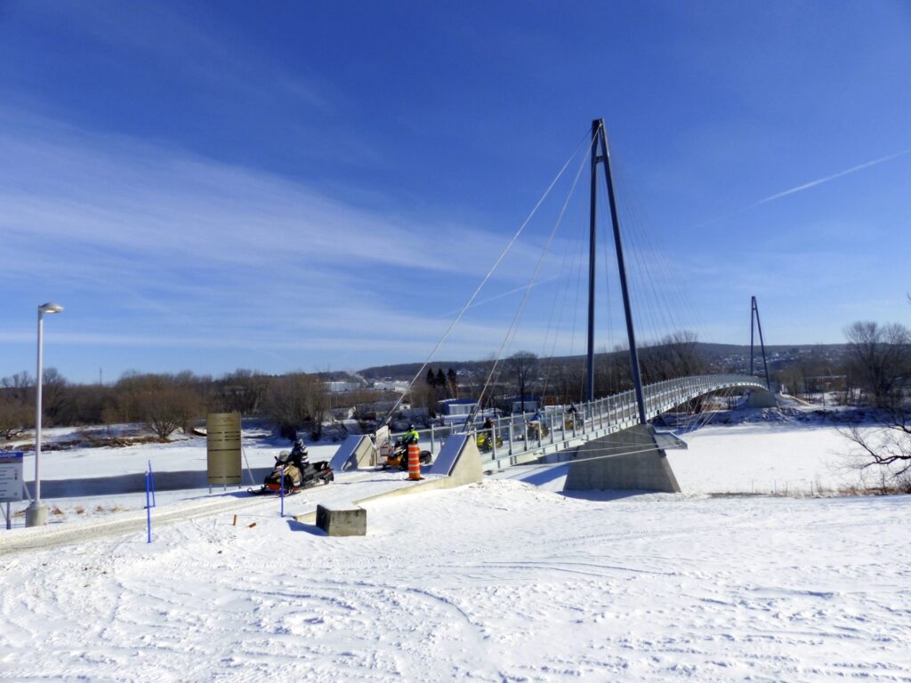 snowmobiles crossing big suspension bridge in Chaudière Appalaches Quebec