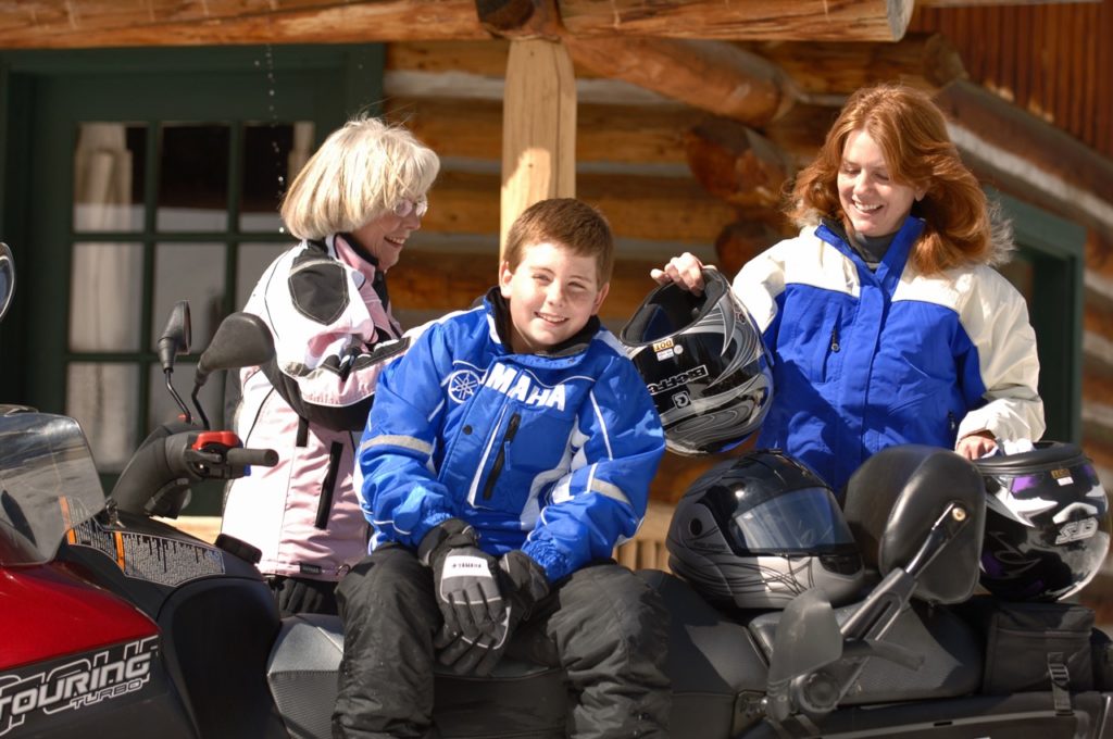 all smiles while snowmobiling with kids