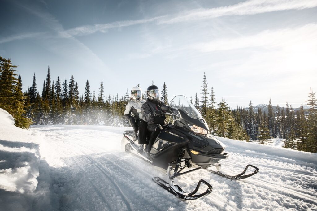 Couple riding 2-up wearing oxygen snowmobile helmets